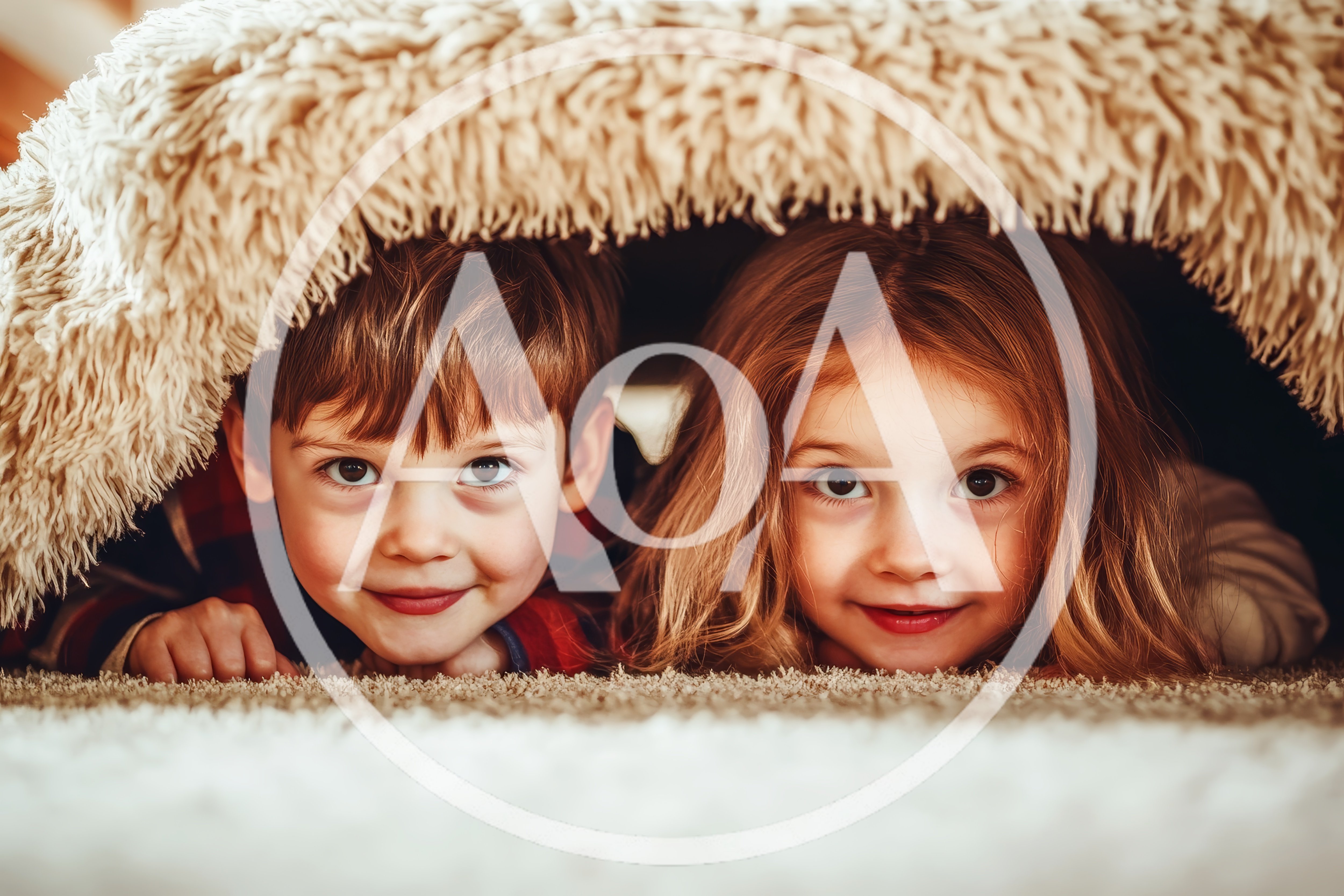 Young Children Hiding Under A Cozy Blanket