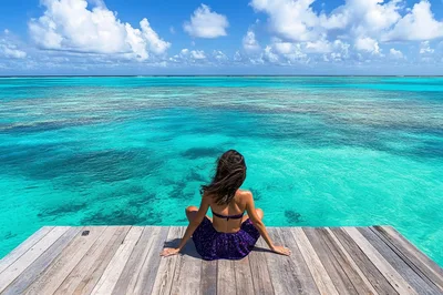 Woman Sitting On Wooden Pier Over Tropical Ocean