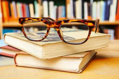 Tortoiseshell Glasses Resting On Stack Of Old Books