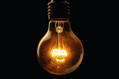 Glowing Incandescent Light Bulb Against Black Background