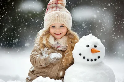 Happy Little Girl Building A Snowman In Winter