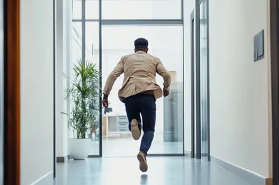 Businessman Running Down A Modern Office Hallway