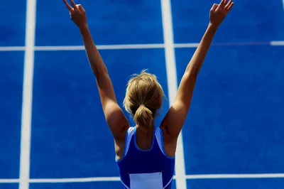 Female Athlete Celebrating Victory on Blue Track