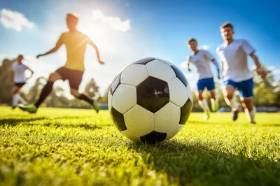 Soccer Players Running Toward Ball on Sunny Field
