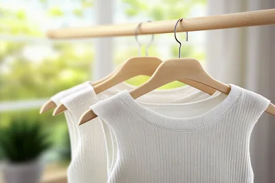 White Sleeveless Knit Tops Hanging On Wooden Hangers