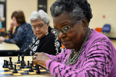Senior Women Playing Chess In A Community Center