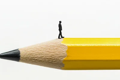 Miniature Business Person Walking On A Pencil Tip