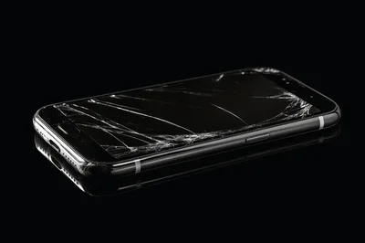 Broken Smartphone Screen On Reflective Black Surface