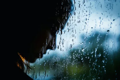 Silhouette Of A Sad Woman Looking Through Rainy Window