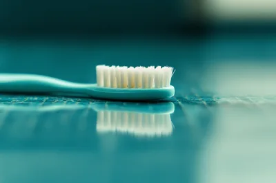 Teal Toothbrush Resting On A Reflective Surface