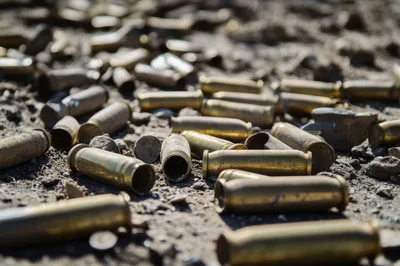 Spent Brass Bullet Casings Scattered On Dirt Ground