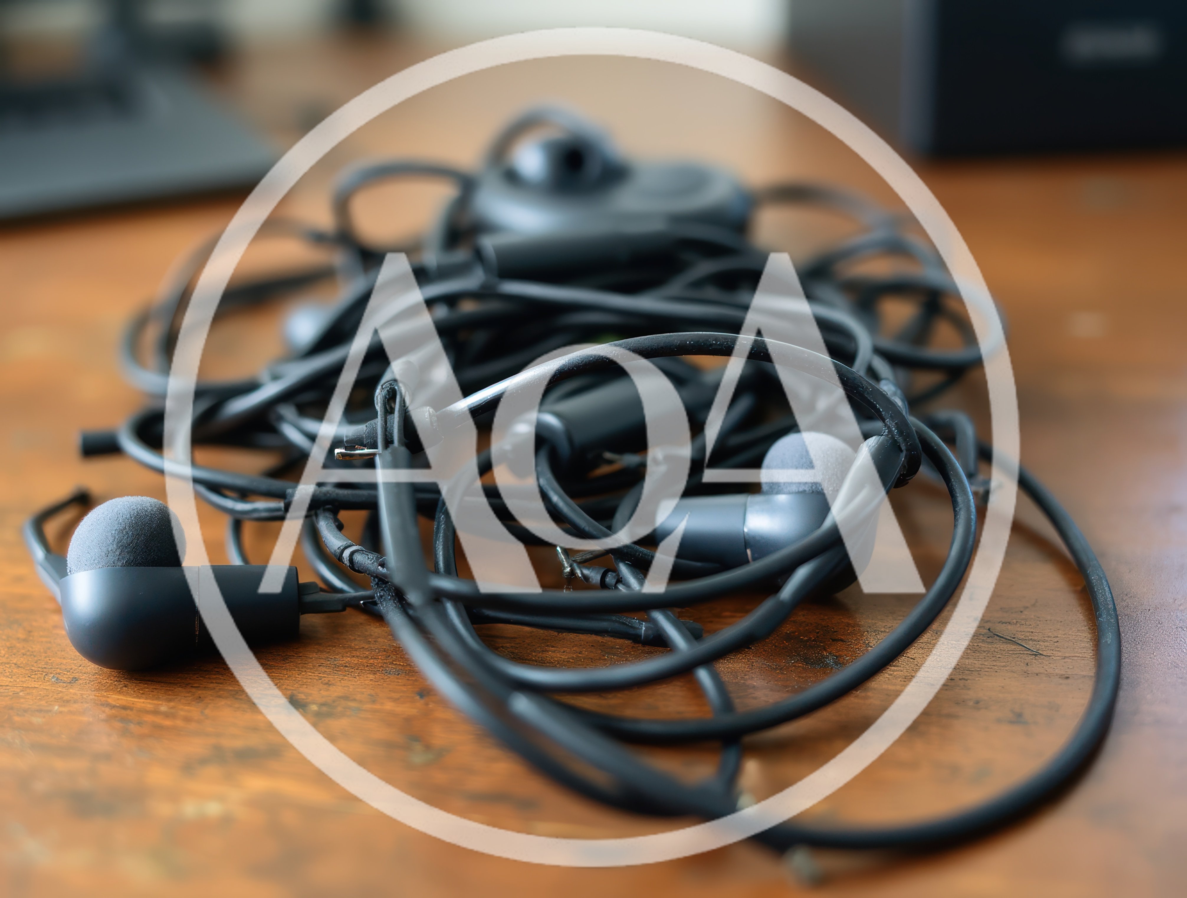 Tangled Black Wired Earphones On Wooden Desk
