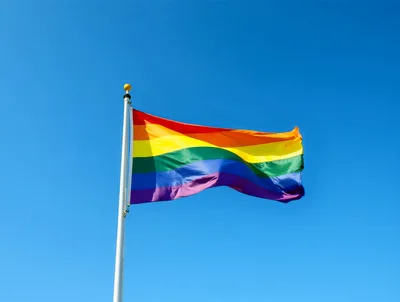 Rainbow Pride Flag Waving Against Clear Blue Sky