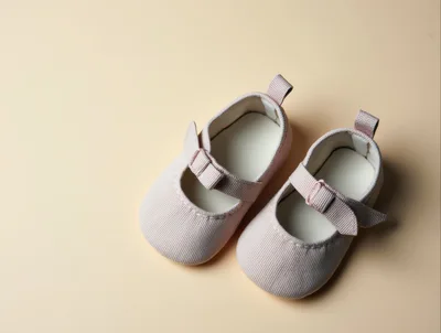 Pair of Pink Baby Shoes on Beige Background