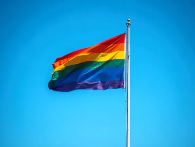 Rainbow Pride Flag Waving Against Clear Blue Sky
