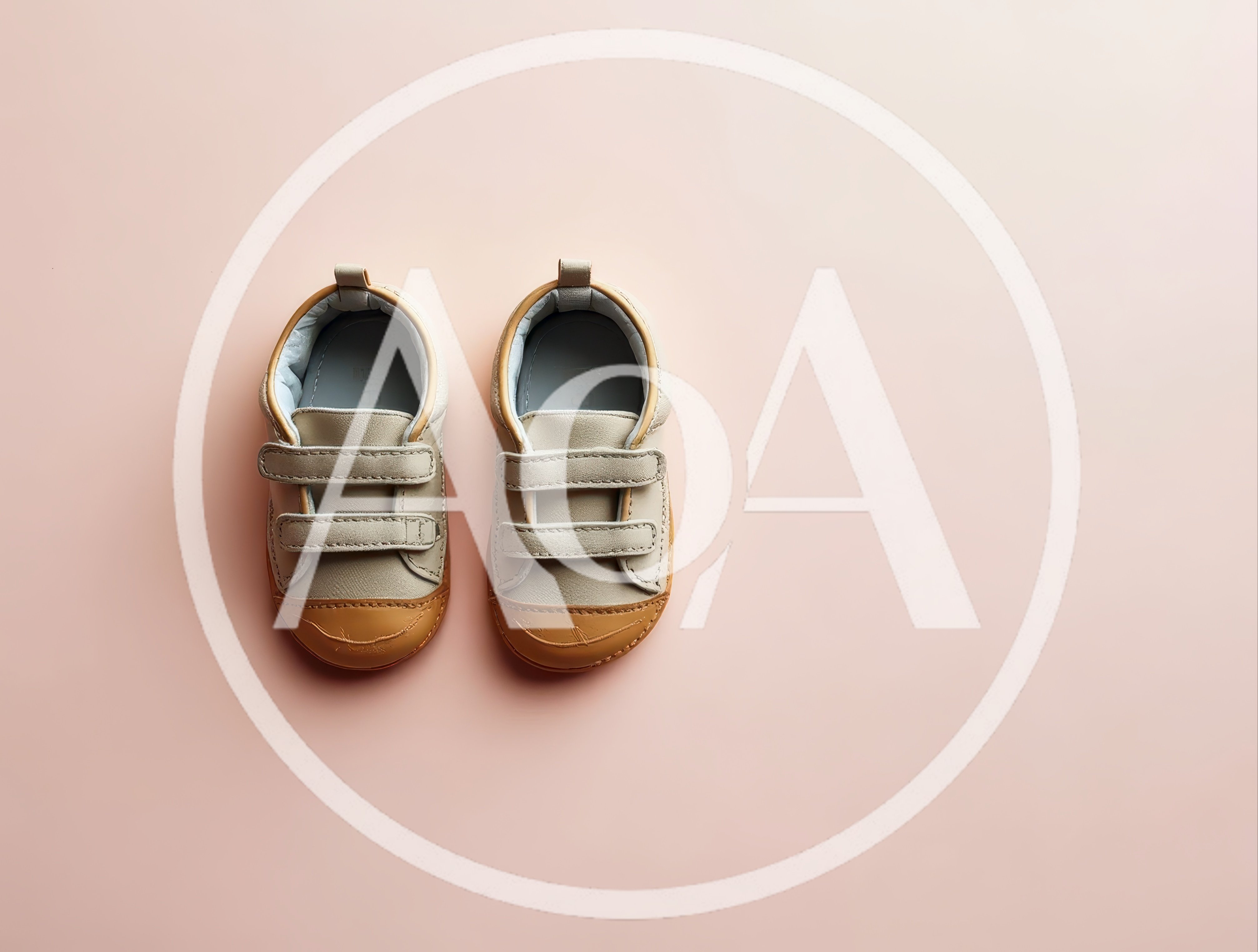 Pair of Beige Toddler Shoes on Pink Background