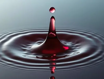 Red Liquid Drop Impact Creating Concentric Ripples