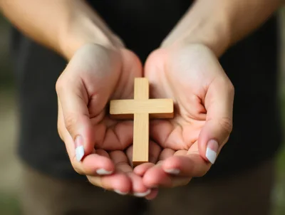 Person Holding A Wooden Christian Cross In Hands