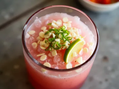 Refreshing Pink Cocktail With Lime And Nut Garnish