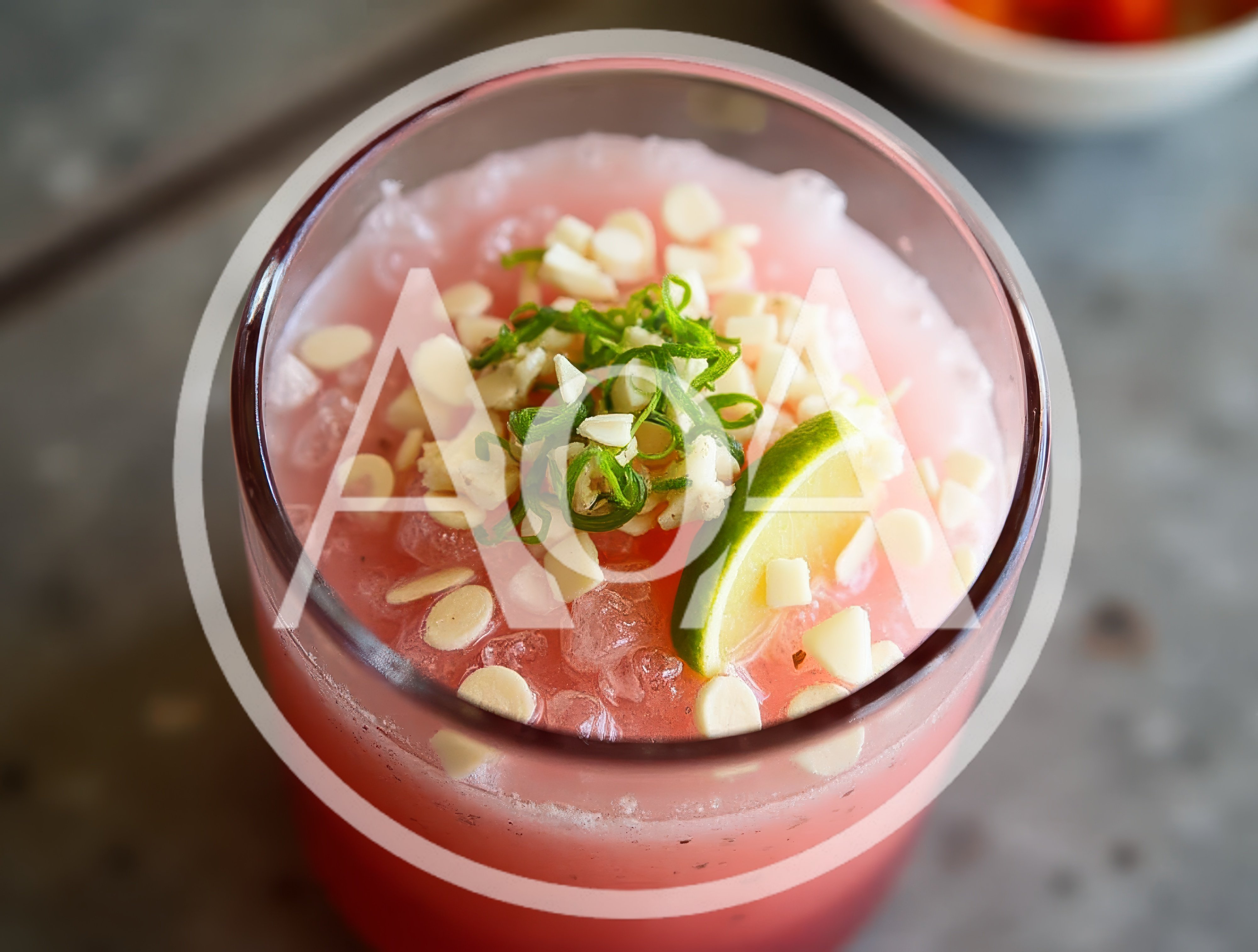 Refreshing Pink Cocktail With Lime And Nut Garnish