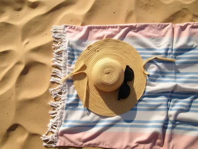 Straw Sun Hat And Sunglasses On Striped Beach Towel
