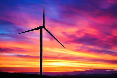 Wind Turbine Silhouette Against A Vibrant Sunset Sky