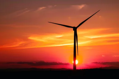 Wind Turbine Silhouette Against A Vibrant Sunset