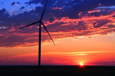 Wind Turbine Silhouette Against A Vibrant Sunset