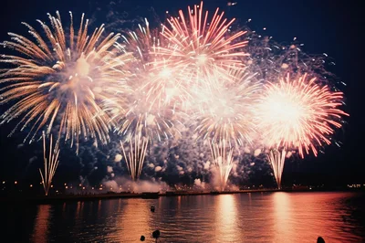 Vibrant Fireworks Display Over A Calm Waterfront