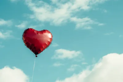 Red Heart Shaped Balloon Floating In Blue Sky