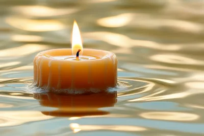 Floating Candle Burning On Calm Water Surface