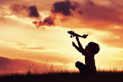 Young Boy Playing With Toy Airplane At Sunset