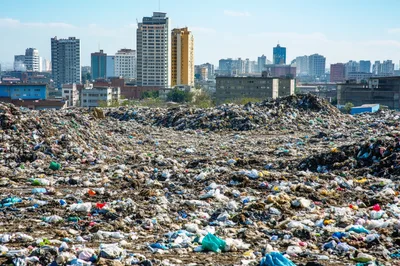 Massive Garbage Landfill Near Urban City Skyline