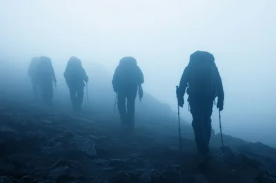 Group Of Hikers Trekking Through Dense Mountain Fog