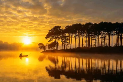 Lone Fisherman In A Small Boat At Sunrise