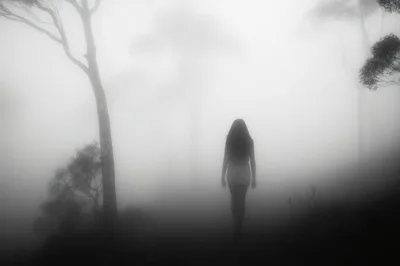 Silhouette Of A Woman Walking Through Dense Fog