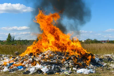 Large Pile Of Burning Trash In An Open Field