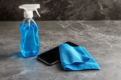 Cleaning Smartphone Screen With Blue Spray And Microfiber Cloth