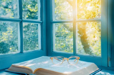 Open Book With Reading Glasses On A Sunny Window Sill