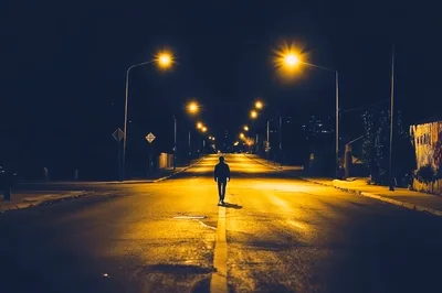 Lone Person Walking Down Empty Street At Night