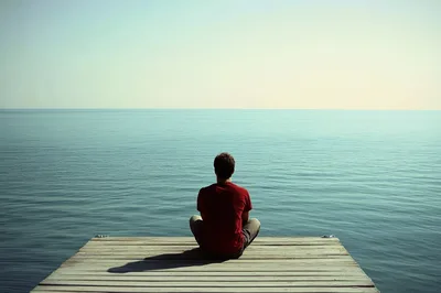 Man Sitting In Meditation On A Wooden Dock