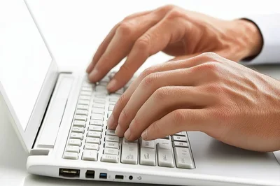 Close Up Of Hands Typing On White Laptop Keyboard