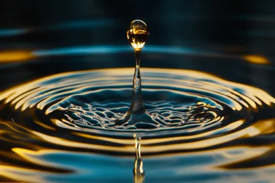 Golden Water Drop Impact Creating Concentric Ripples