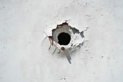 Damaged White Stucco Wall With Circular Hole