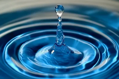 Blue Water Drop Impact Creating Concentric Ripples