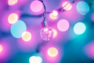 Single Glowing Light Bulb With Colorful Bokeh Background