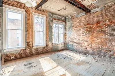 Dilapidated Room With Exposed Brick Walls And Windows