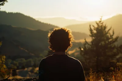 Person Looking At Sunset Over Mountain Landscape