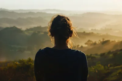 Woman Looking Over Misty Rolling Hills At Sunrise