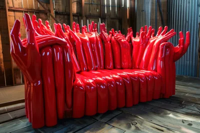 Surreal Red Hand Sculpture Sofa In Rustic Workshop